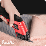 Electro fabric cutting tool by Haeri in use, cutting soft pink fabric on a grid surface.